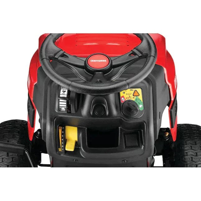 Craftsman T110 riding lawn mower with a 42-inch cutting deck, shown in a well-maintained yard with grass and garden tools.
